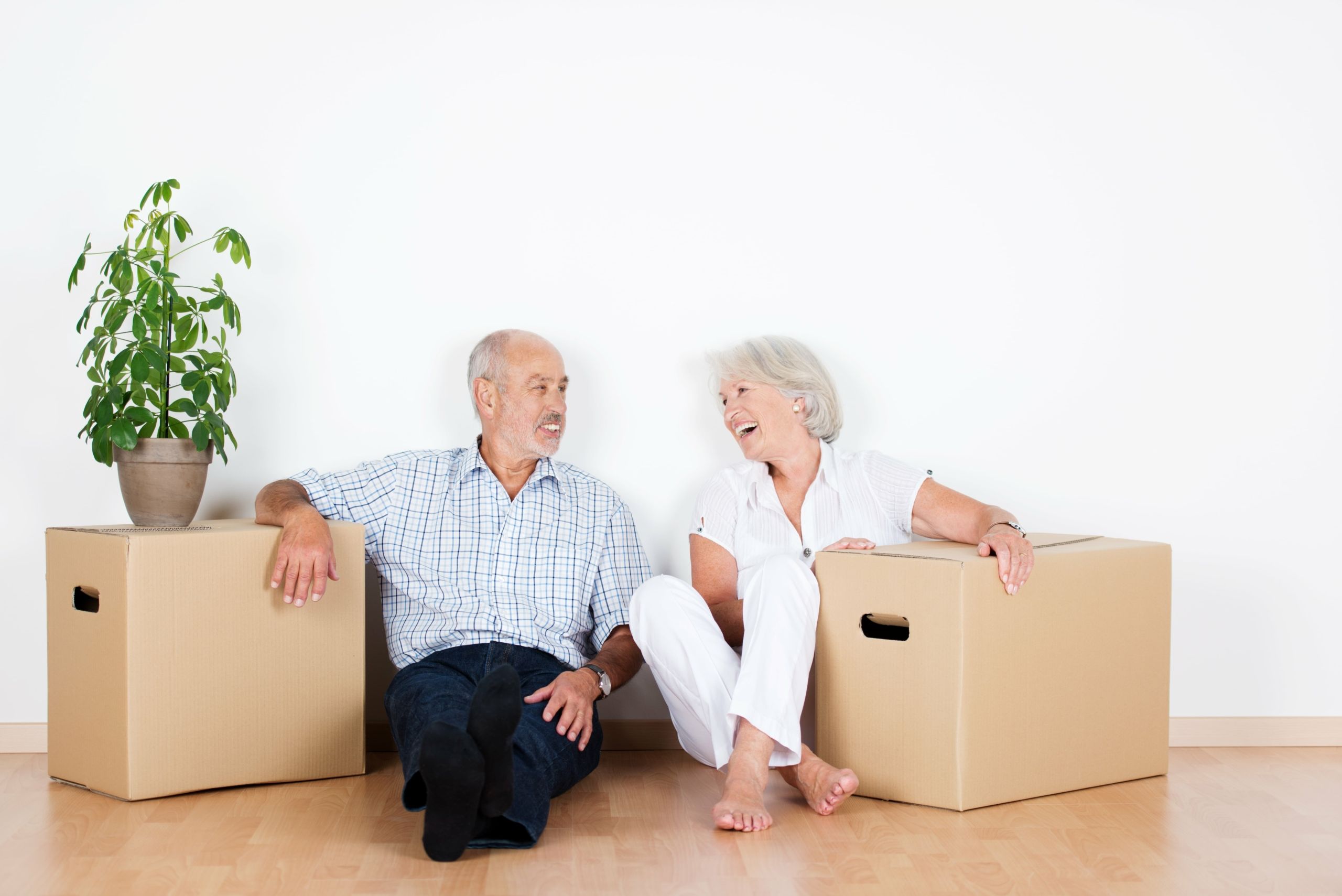 Couple sit on the floor between new boxes used to move house